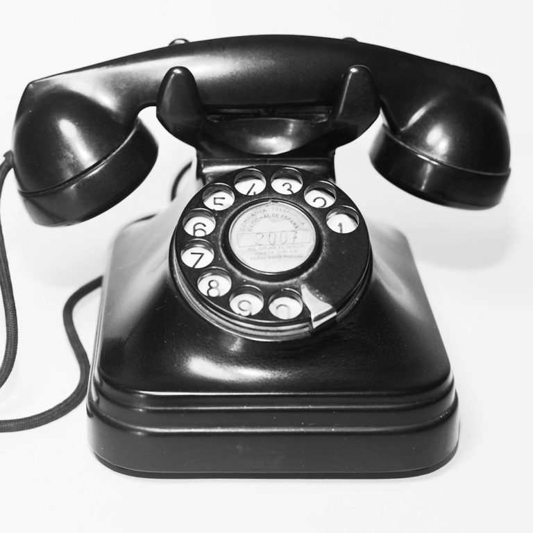 Schwarzes Vintage-Telefon mit Wählscheibe und zwei Hörern.